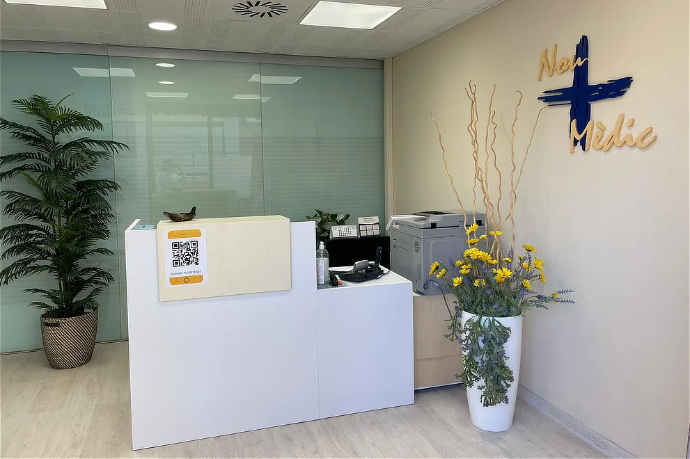 Recepción de la clínica Oftalmediq en Hospitalet con mostrador blanco, código QR y logotipo de New Médic; especialistas en oftalmología en L'Hospitalet de Llobregat.