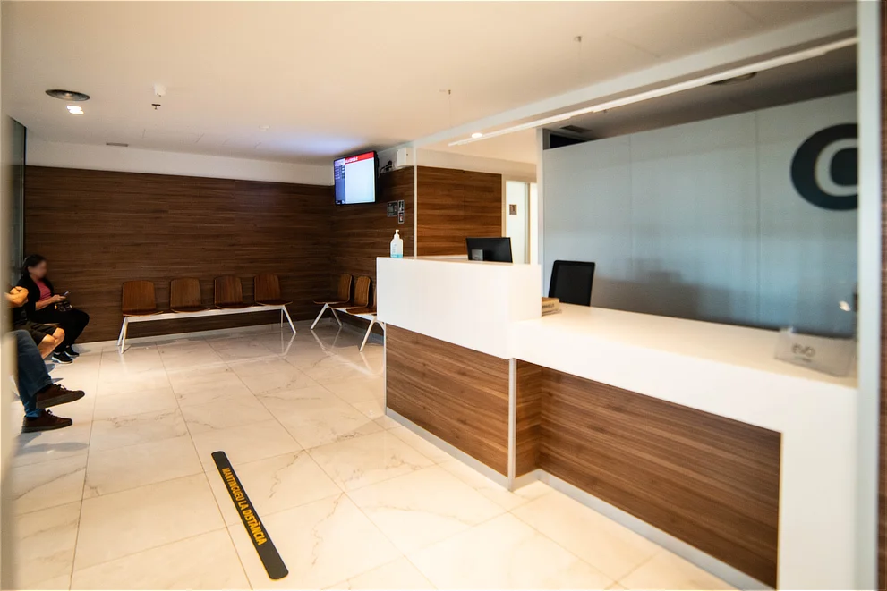 Sala de espera moderna con acabados en madera y suelo de mármol en Oftalmediq Terrassa; atención oftalmológica integral en Terrassa.