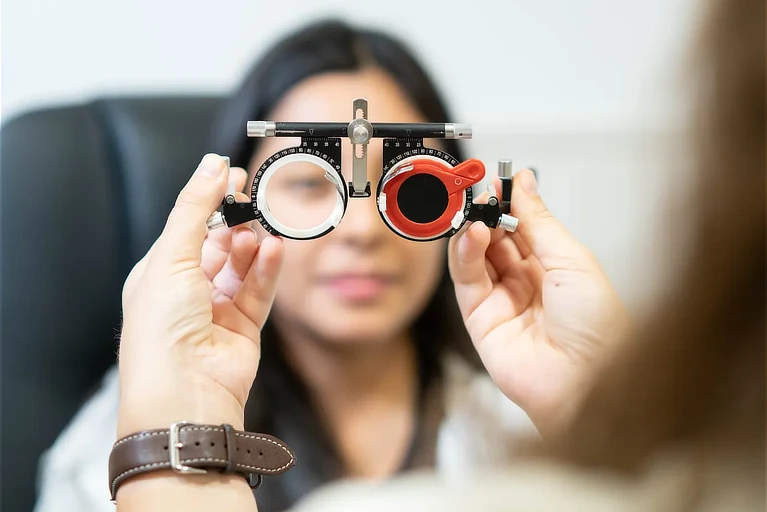 Profesional de optometría realizando una prueba de graduación visual con foróptero durante una revisión ocular en consulta especializada.