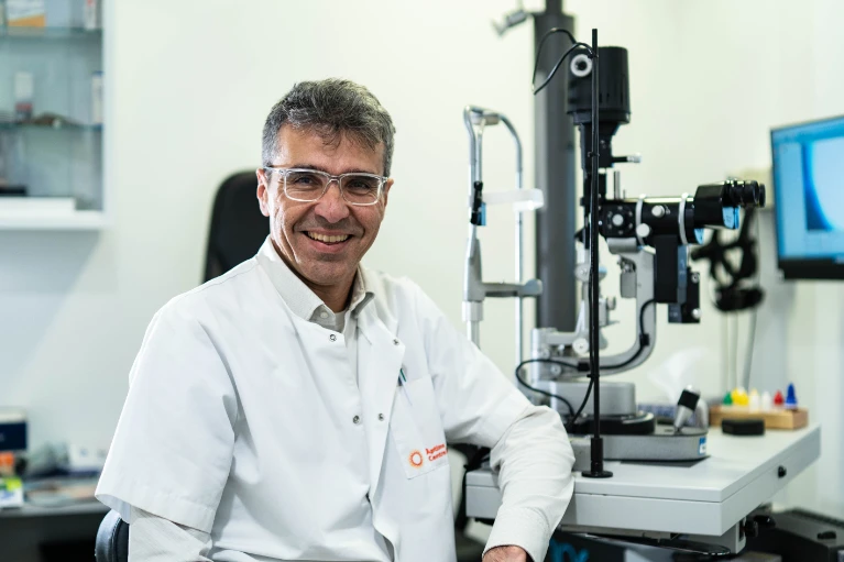 José Luis Macaya Pascual, profesional de Oftalmediq, sonriendo en su despacho equipado con tecnología de diagnóstico oftalmológico avanzada.