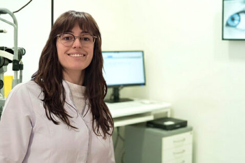 Mireia Costa, miembro del equipo de Oftalmediq, sonriendo en un gabinete óptico con equipos de diagnóstico de última generación.